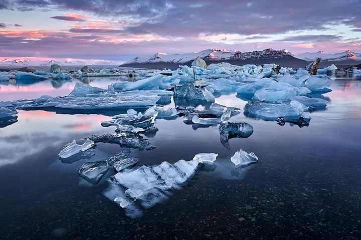Boat tour passengers beside floating icebergs on a Jökulsárlón glacier lagoon boat tour in South East Iceland