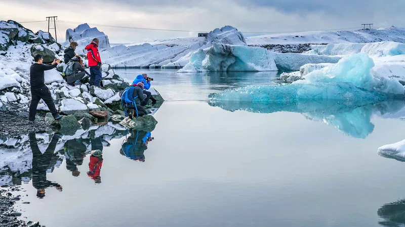 Visitors walking the shore of a Jökulsárlón glacier lagoon boat tour stop with icebergs in South East Iceland