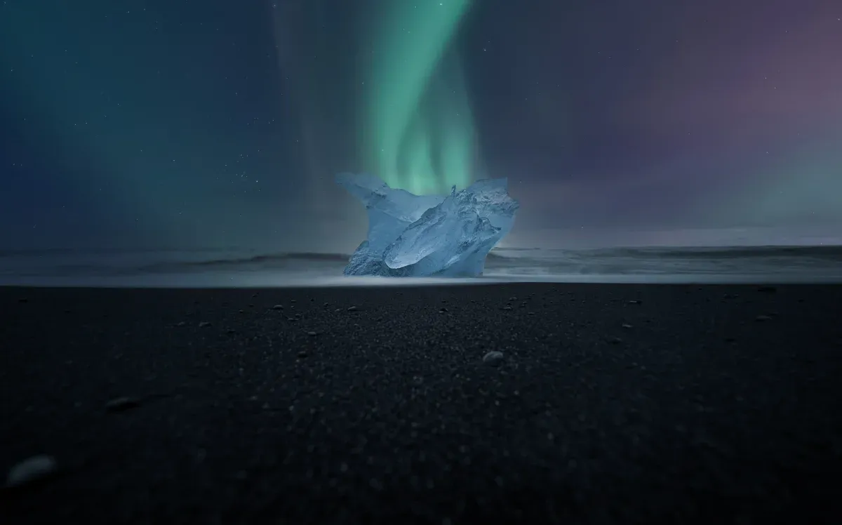 Ice on the black sand of Diamond Beach under the northern lights, across the road from the Jökulsárlón glacier lagoon boat tours